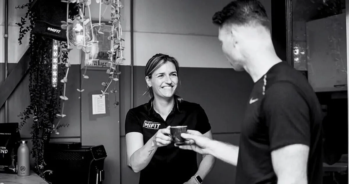 Een medewerker van Mifit geeft een lid een kop koffie